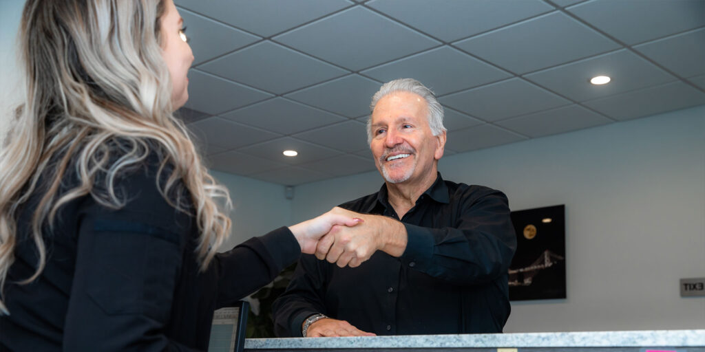 Patient and staff member shaking hands after dental implant procedure within the dental practice